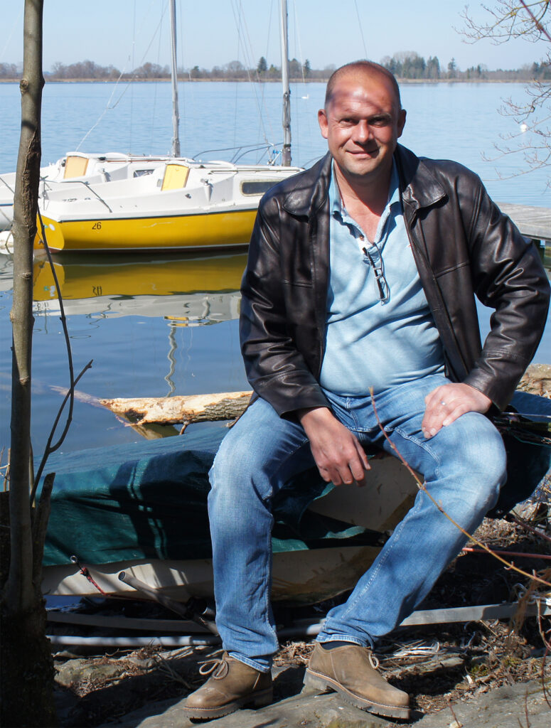 Axel Platzek sitzt vor einem Segelboot. Er hilft beim Segelboot kaufen: Beratung und Tipps
